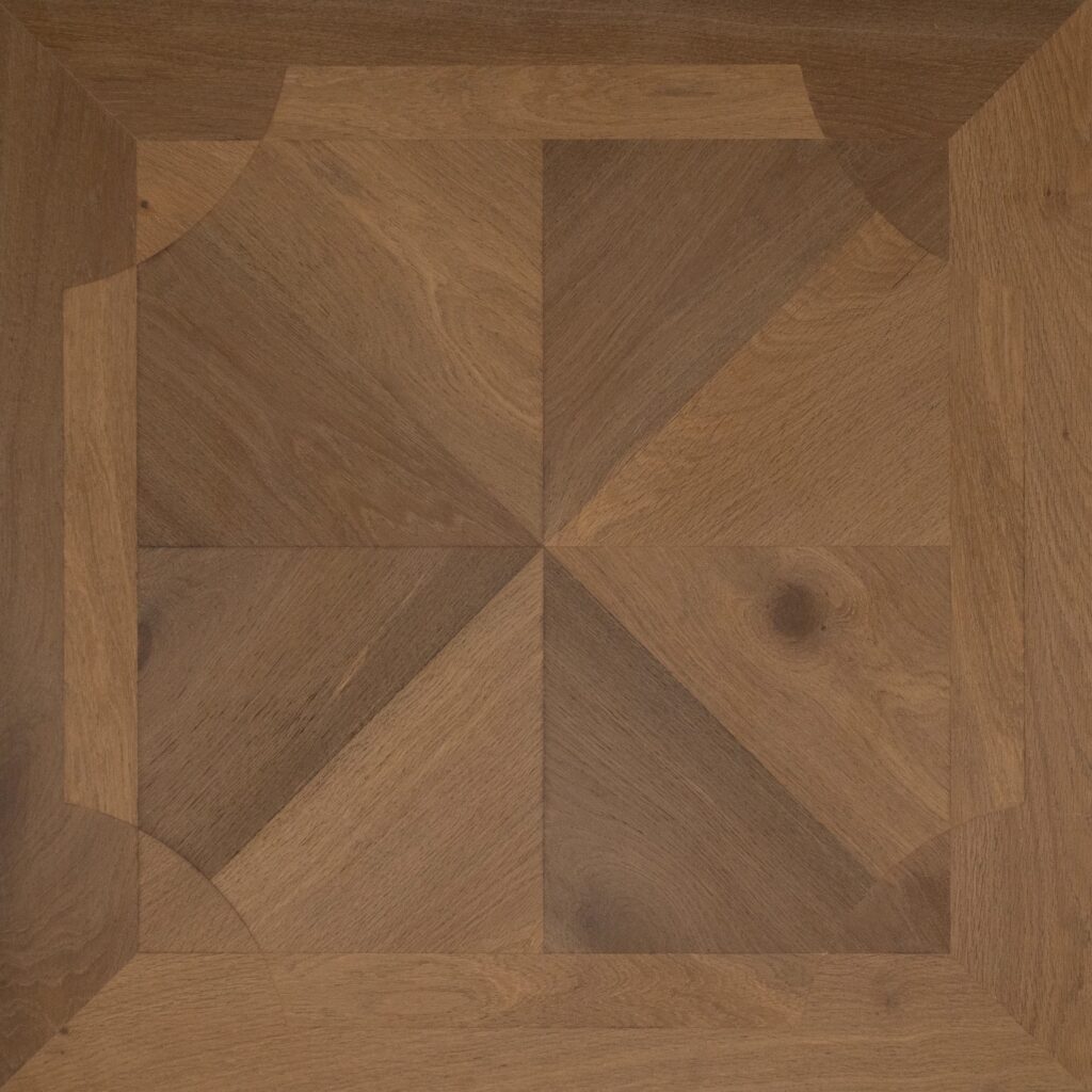 A close-up of a geometric wood parquet pattern with concentric squares and triangular sections in warm medium brown tones, showing natural wood grain and knots.