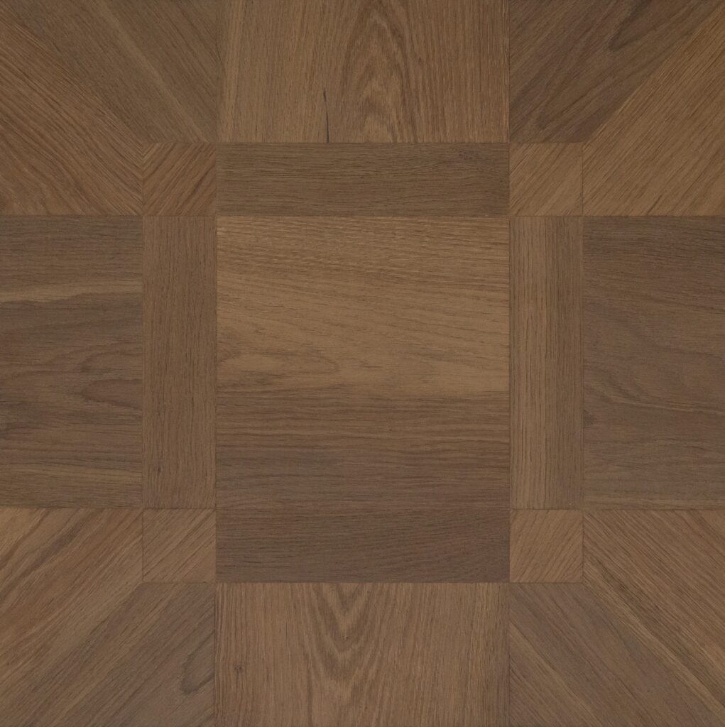 Medium brown wood parquet flooring with a geometric pattern of square and chevron-shaped planks showing natural grain textures.