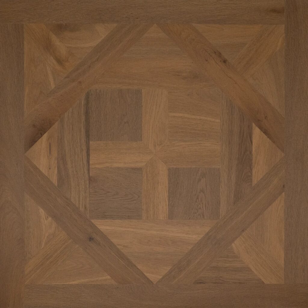 A close-up of a geometric wood flooring pattern with concentric diamond and cross motifs in warm medium brown tones.